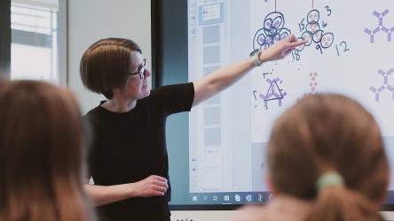 Lærer som peker på en tavle foran sine elever