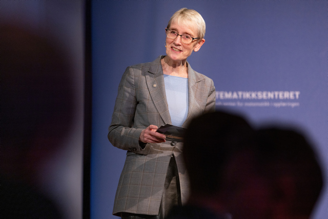 NTNUs rektor Anne Borg står på en scene, med mikrofon. Hun har blå bluse og grå dressjakke. 