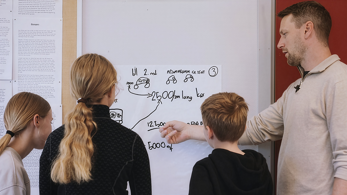 Tre elever og en lærer diskuterer ved en vertikal tavle.