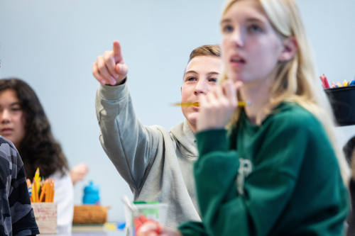 Gutt og jente som sitter i et klasserom og gutten peker på tavla