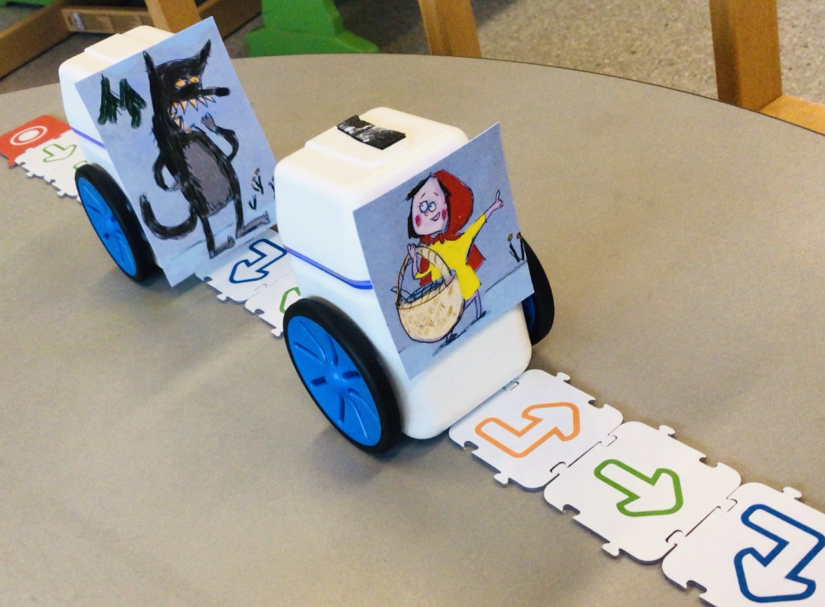 To KUBO-roboter med påklistrede tegninger. Roboten bak har en tegning av en ulv og roboten foran har en tegning av Rødhette. 