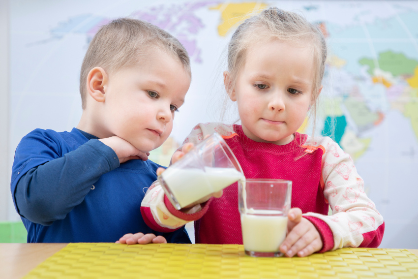 Barn tømmer melk fra ett glass til et annet