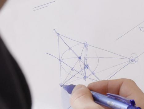 VI ser noen som tegner en geometrisk figur på et hvitt ark. 
