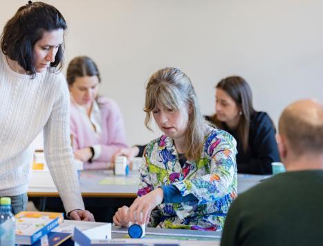 To kvinner som sitter i et rom og jobber med KUBO (robot)