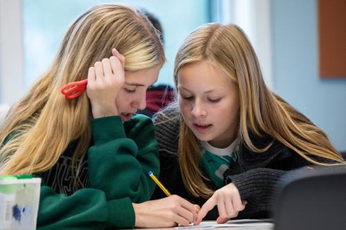 To jenter i 12-årsalderen som sitter og jobber med en matematisk oppgave