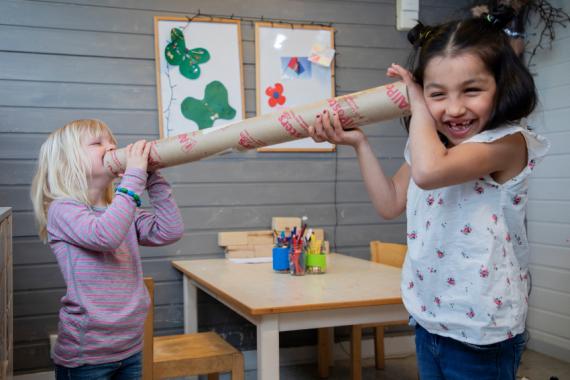 Barn snakkar med kvarandre gjennom papprøyr