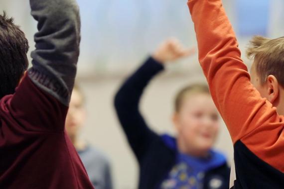 Bilde av barn som rekker opp hånda i et klasserom