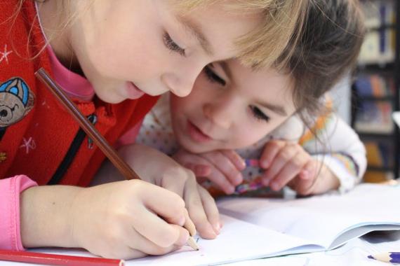 Illustrasjonsbilde av to små jenter som skriver i en skrivebok. 