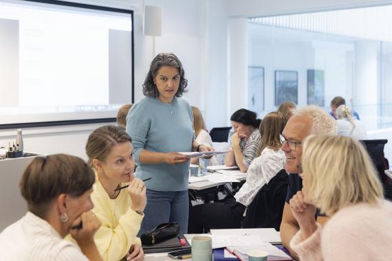 Elham kazemi går rundt i klasserommet og lytter til gruppearbeid.