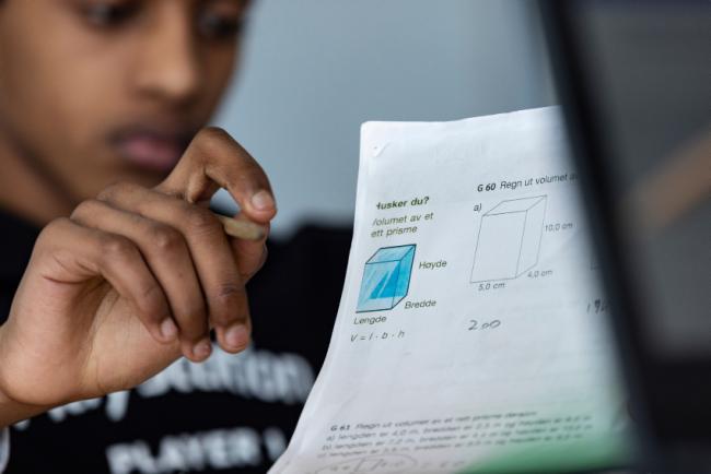 Gutt som ser på et ark med matematikkoppgaver