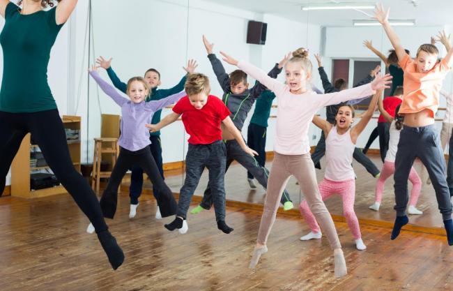 Flere barn og en voksen som danser i en gymsal