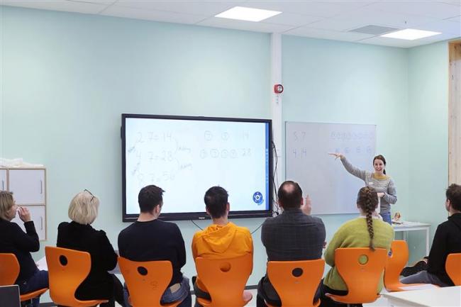 Lærere som sitter foran en smartboardtavle, med ryggen til