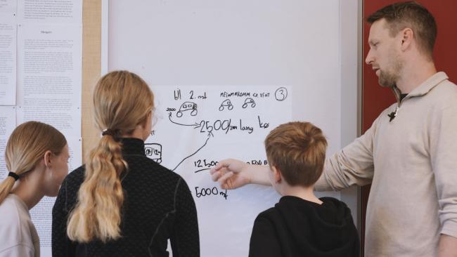 Lærer viser tre elever modellering på tavla.