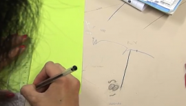 Elev som tegner en strek på et gult ark ved hjelp av en linjal. 