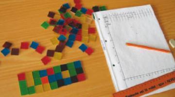Bilde av elevarbeid med kvadratiske tellebrikker og en tabell