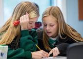 To jenter i 12-årsalderen som sitter og jobber med en matematisk oppgave
