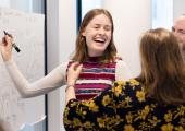 Lærere som ler og skriver på en vertikal tavle