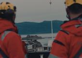 To arbeidere på et tak kikker utover Trondheimsfjorden mot Munkholmen