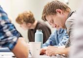 Student som leser ved en pult. Andre studenter synes i bakgrunnen. 
