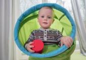 Liten gutt som står inne i et grønt tøy-rør